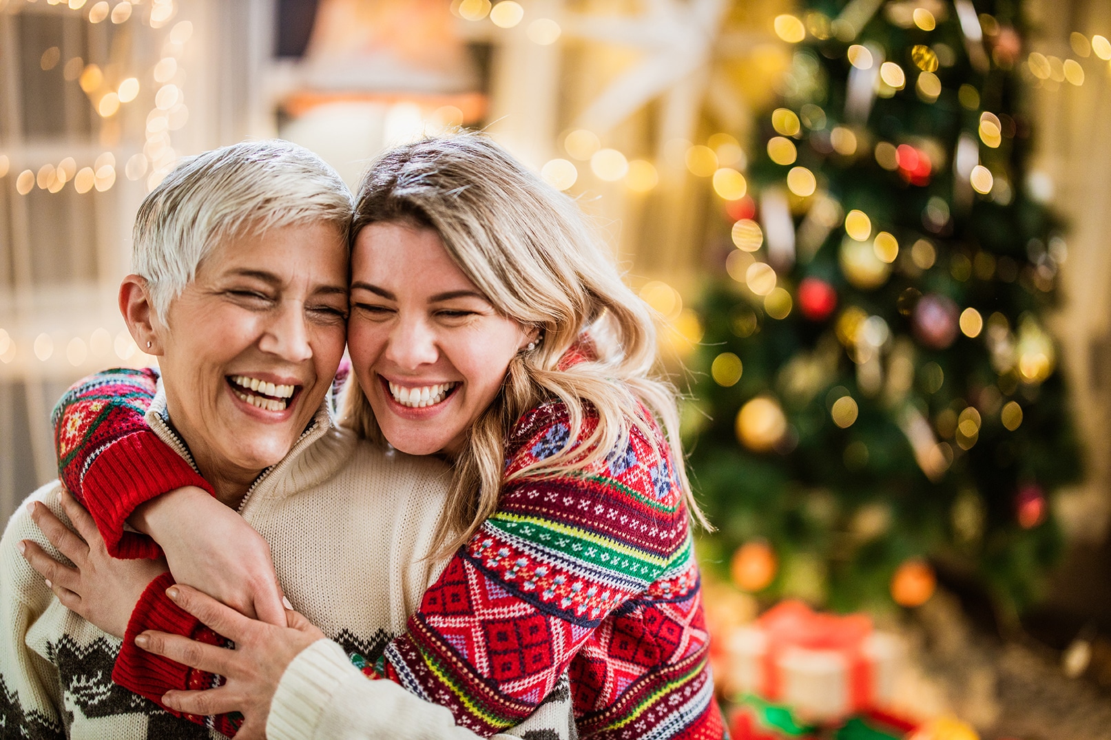 Affectionate adult daughter embracing her mature mother on Christmas day at home.