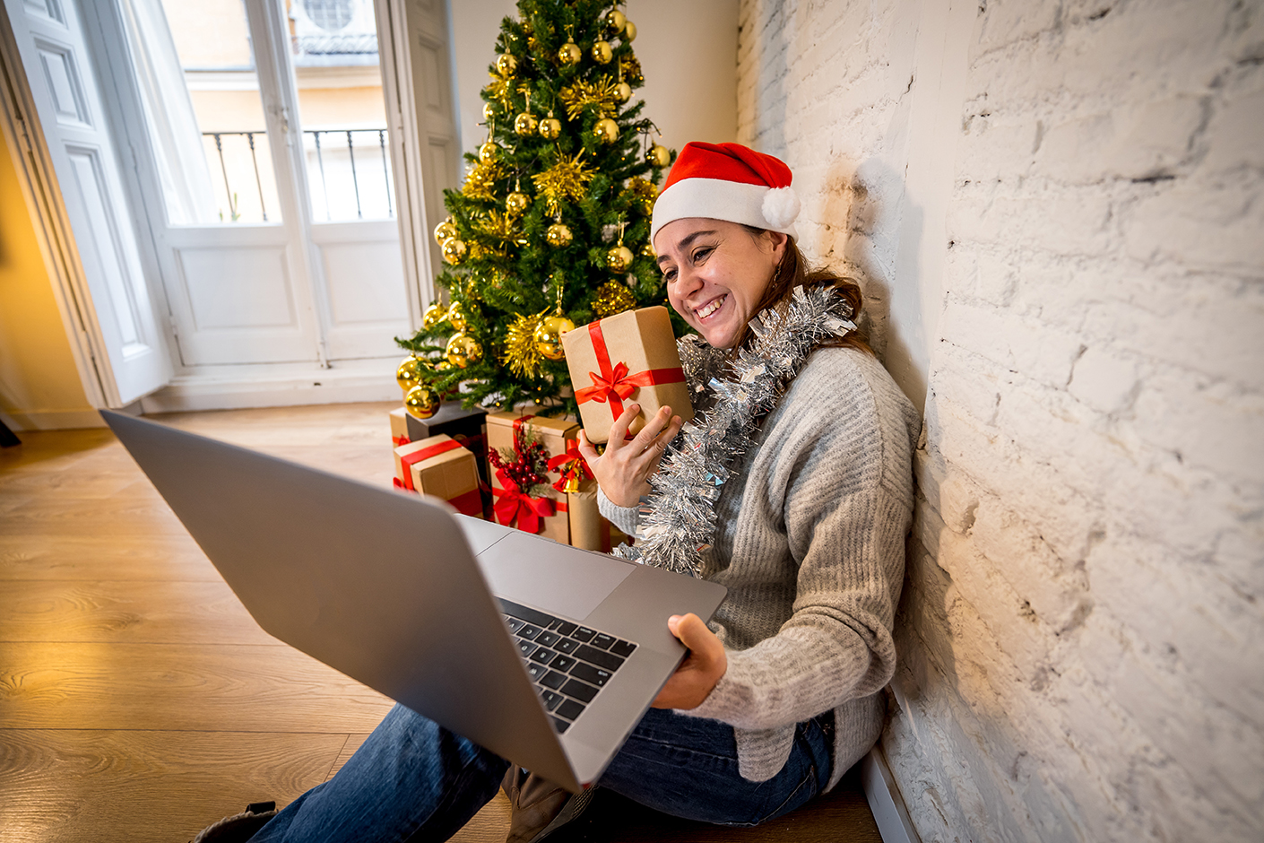 Happy woman alone in lockdown celebrating virtual christmas video calling family and friends.