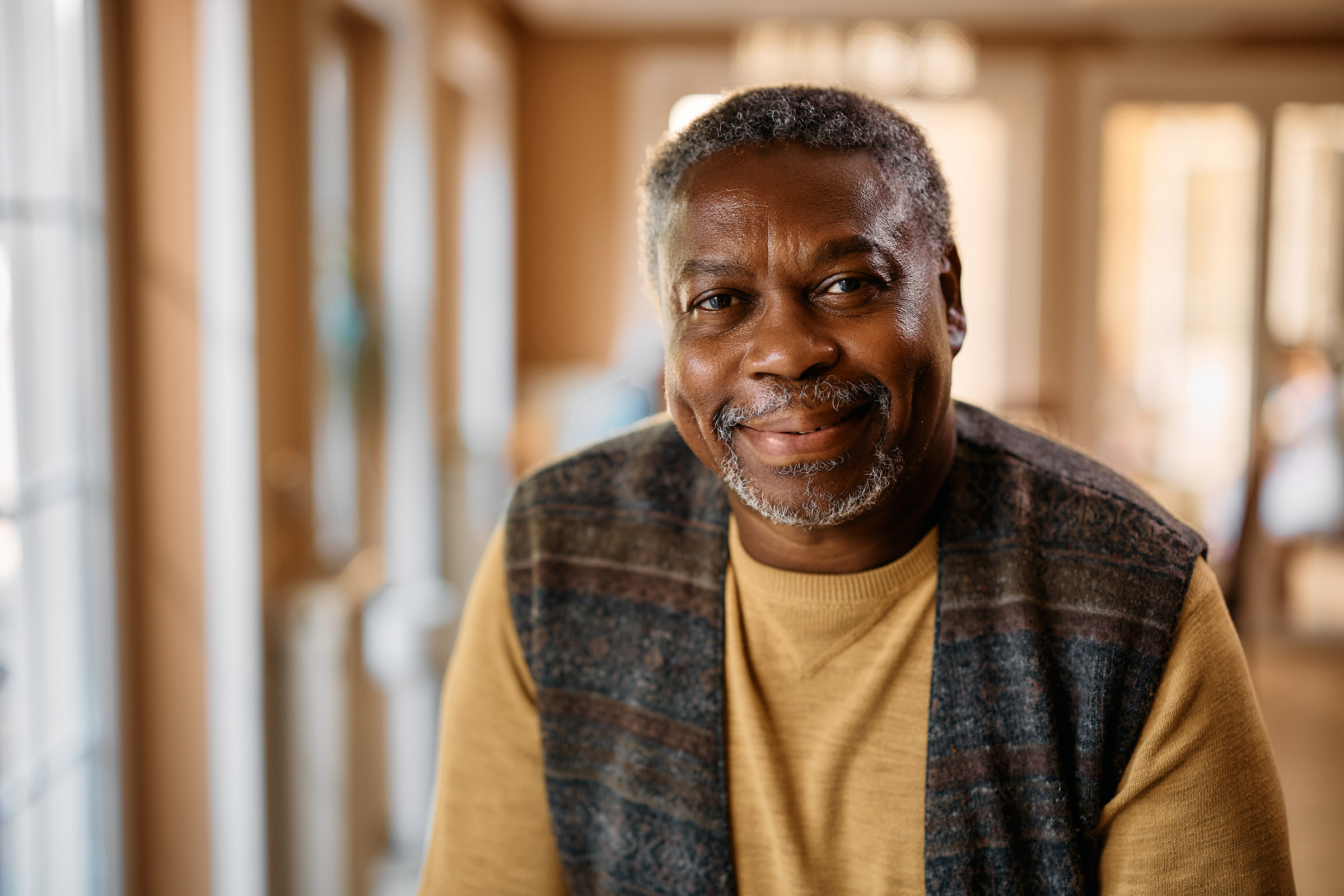 An older man in a vest smiling